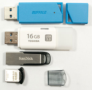 USBメモリー。正面、キャップ取り外し。BUFFALO 8GB キャップ外し。TOSHIBA 16GB キャップ背後にはめ込み。SanDisk 16GB キャップ無し ストレート。SanDisk 64GB キャップ外し。